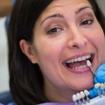 Dentist matching a dental crown shade against a patient’s tooth at One Dental Place, Fresno, CA 93720