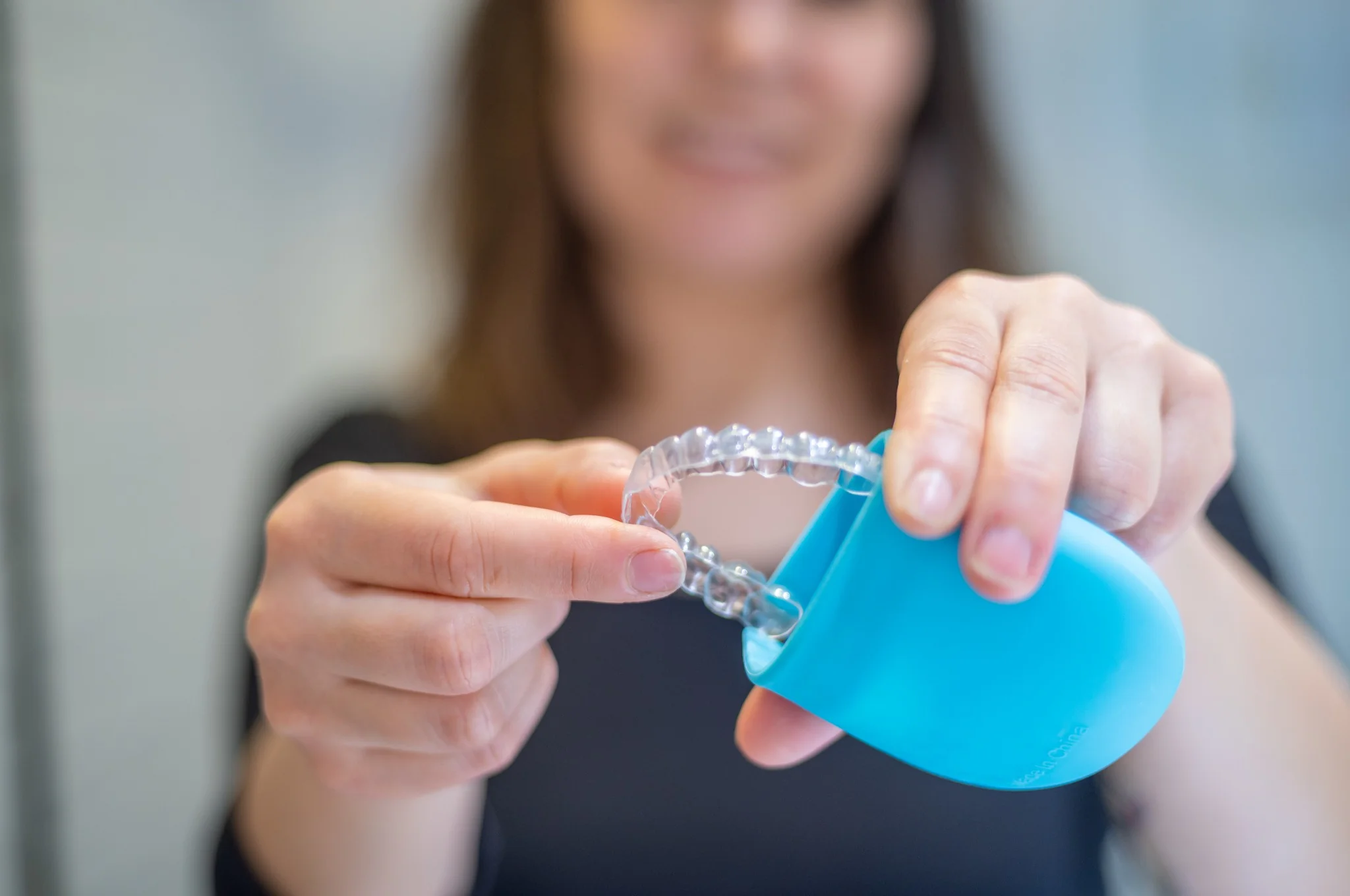 Woman placing a clear mouthguard into a storage case