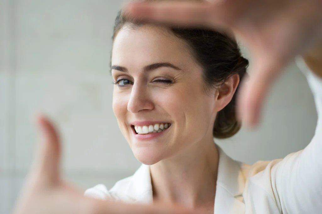 Smiling woman framing her face to show teeth whitening results